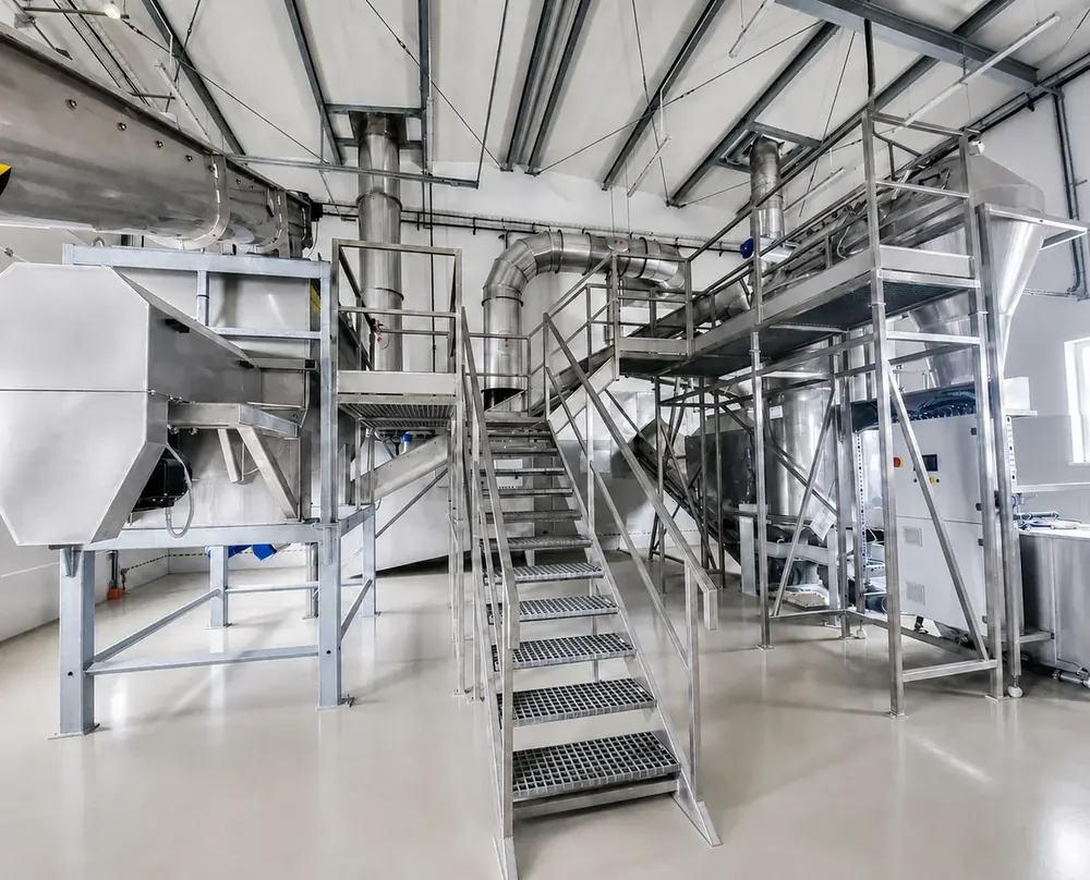 Wnętrze instalacji FuelCal® w Kole: przenośniki, zbiorniki, schody i podesty technologiczne